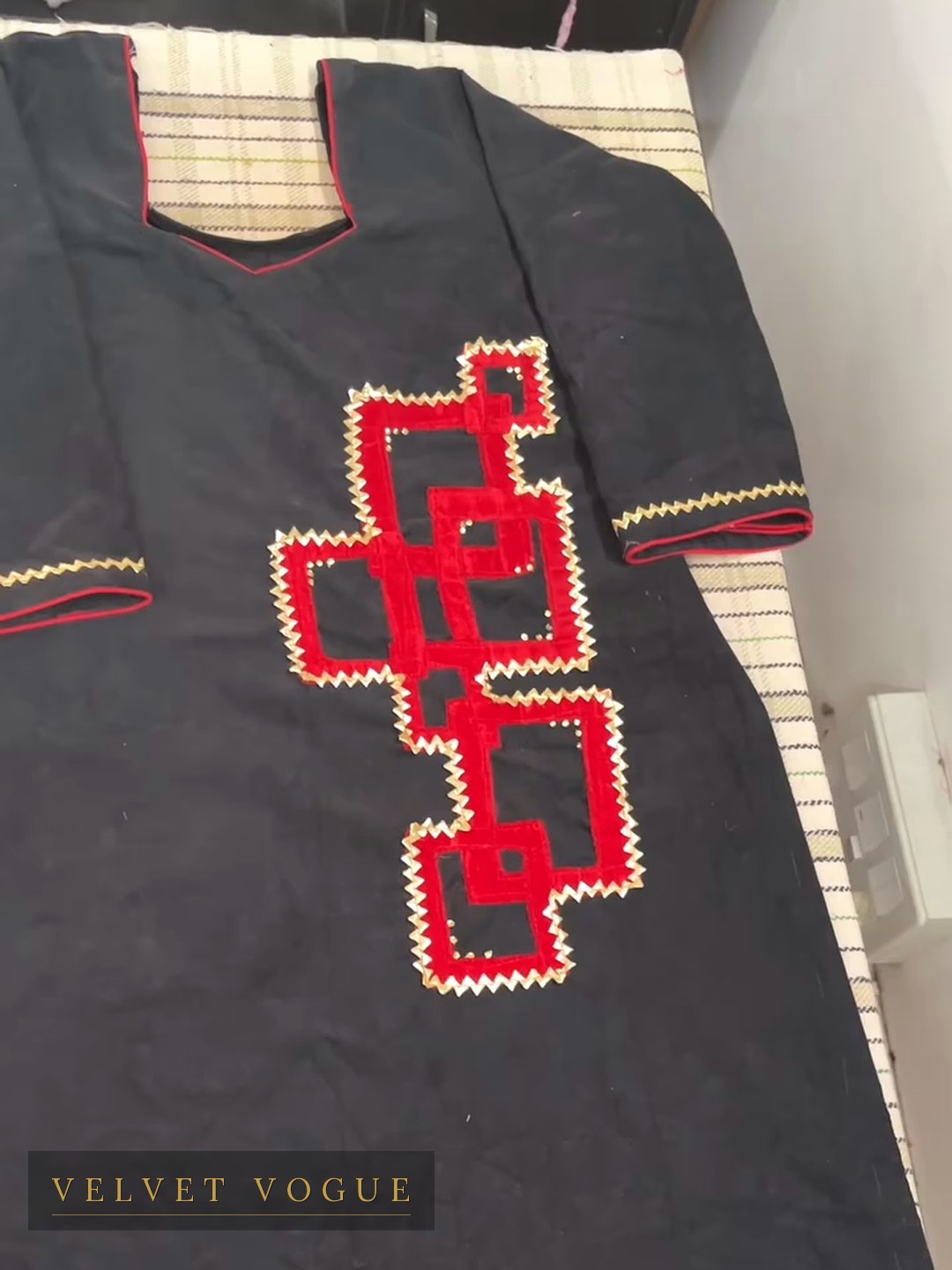 Red appliqu&eacute; laid onto black and outlined in a hand-run zigzag — a Phulkari figure, reworked.