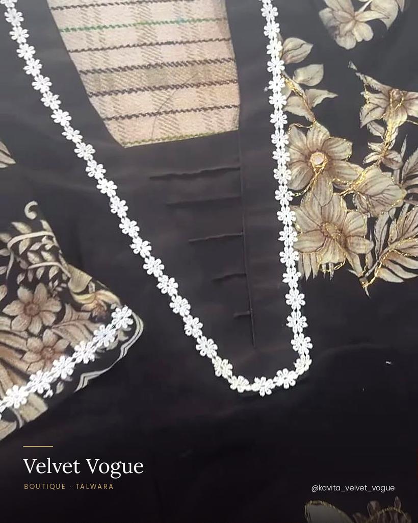 A white floral chain following the V-neck, set over pintucks.